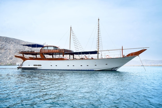 Yacht bianco nel mare blu Cielo blu del mare e montagne Concetto di svago e turismo di relax