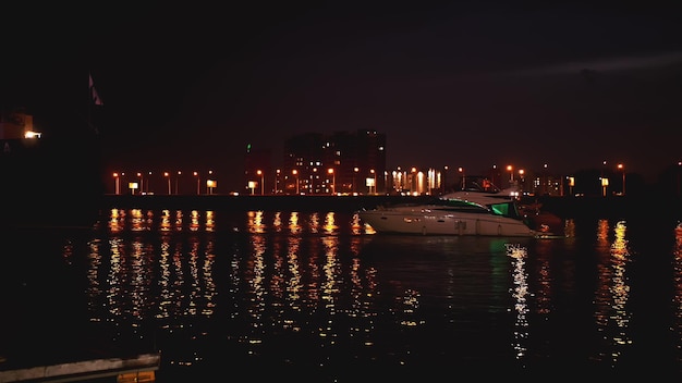 Yacht e barca privati moderni e lussuosi al molo di notte Skyline di attraversamento della nave nel porto
