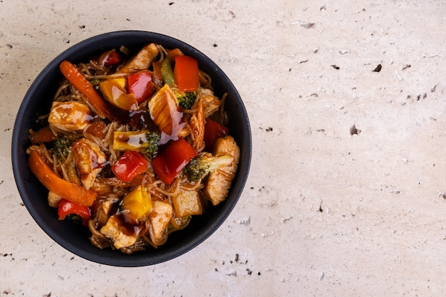 Yakissoba di pollo in ciotola di ceramica nera - vista dall'alto.