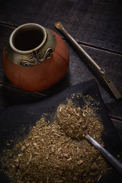 Yerba mate e zucca con bambilla su fondo di legno nero