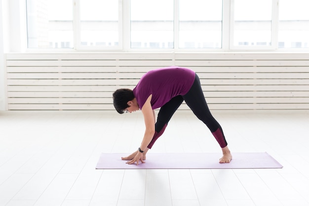 Yoga, concetto di persone - una donna di mezza età che fa yoga e prova a fare un asana.