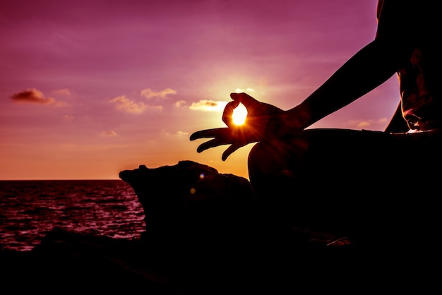 Yoga della donna della siluetta sul tramonto della montagna. Sport e stile di vita sano.