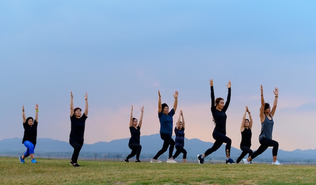 Yoga delle donne del gruppo nel lago sunset