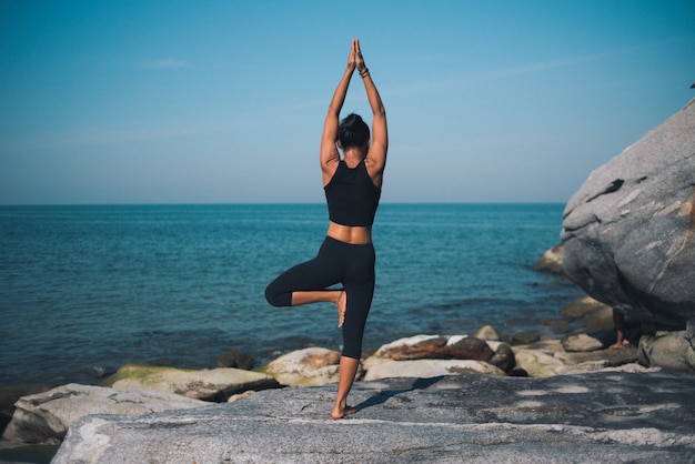 Yoga di pratica della donna asiatica sulla spiaggia