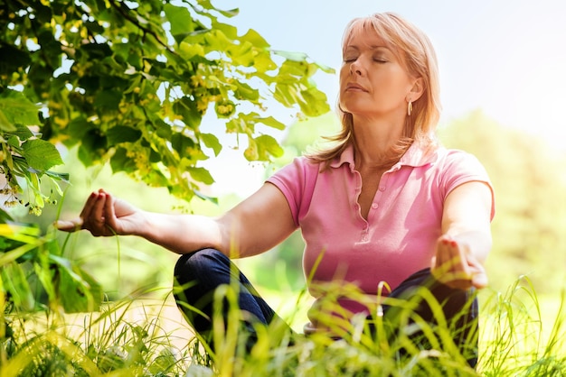 Yoga di pratica della donna matura nel parco