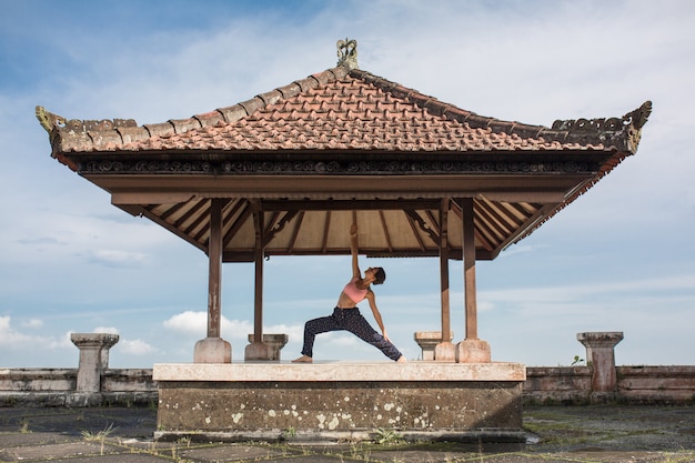 Yoga di pratica della donna nel gazebo tradizionale di balinesse