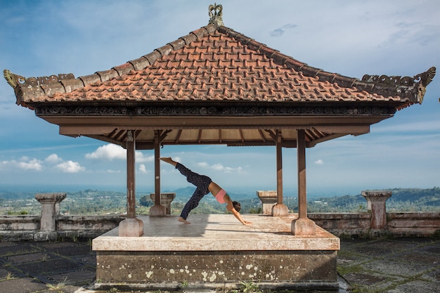 Yoga di pratica della donna nel gazebo tradizionale di balinesse.