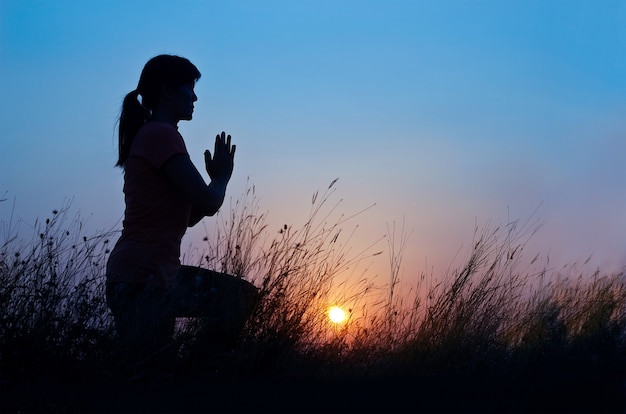 Yoga di pratica della donna sui precedenti blu di tramonto