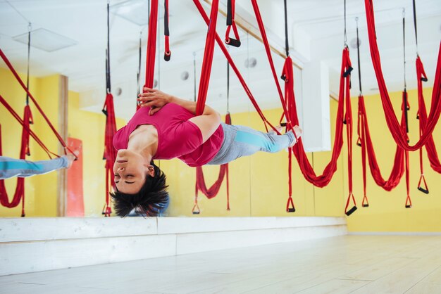 Yoga di pratica della giovane bella donna Vola con un'amaca. Volare, fitness, allungamento, equilibrio, esercizio fisico.