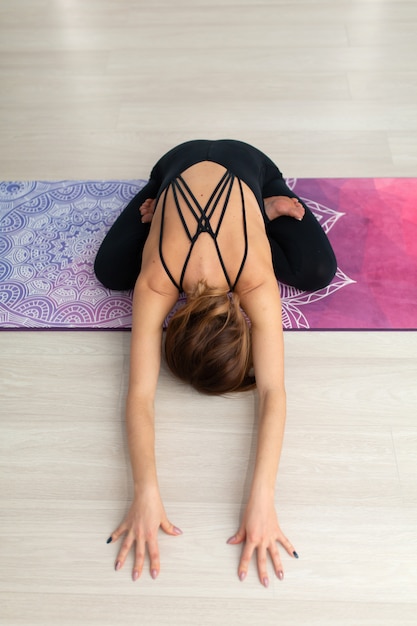 Yoga di pratica della giovane donna che allunga in palestra