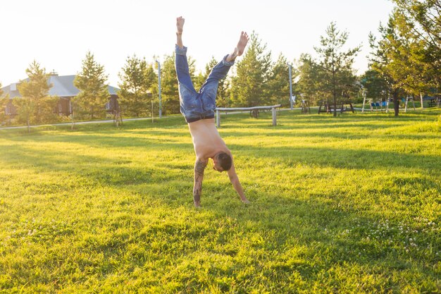 Yoga, fitness e concetto di stile di vita sano - uomo che fa una verticale sulla natura estiva.