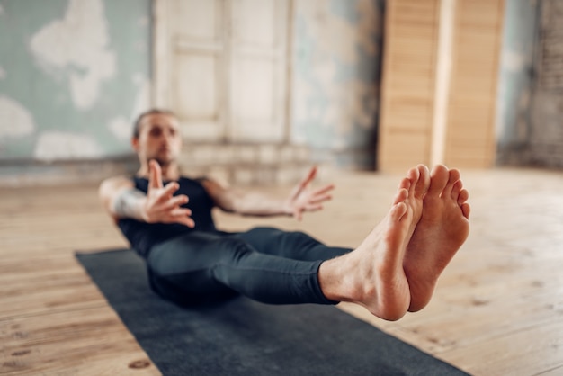 Yoga maschile in classe, press training. Esercizio sulla stuoia in palestra con interni grunge. Allenamento in forma al chiuso