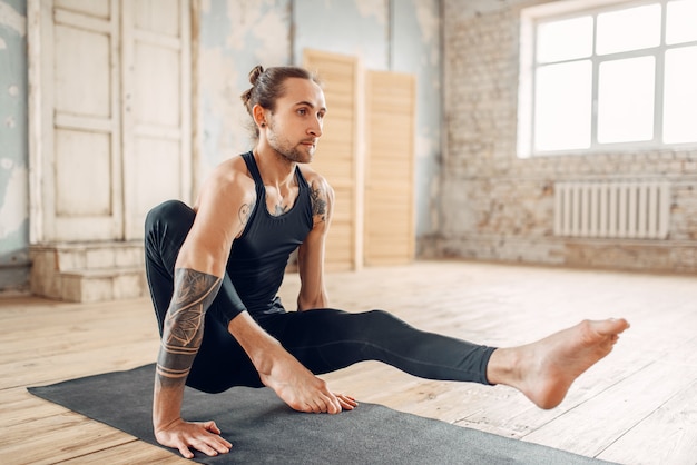 Yoga maschile rilassarsi in palestra, esercizio di equilibrio sulla stuoia. Allenamento fitness al chiuso. Stile di vita sano, meditazione