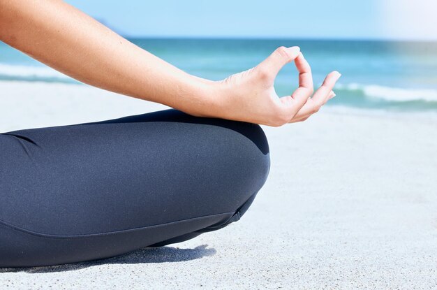 Yoga medita e mano zen sulla spiaggia per il chakra e l'allenamento del benessere in riva all'oceano sabbia e mare Donna nella natura per la salute della mente esercizio fisico e allenamento della respirazione in estate per la consapevolezza e l'equilibrio