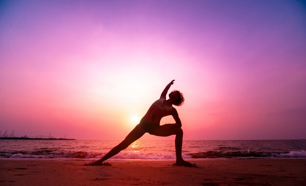 Yoga pratica della bella giovane donna alla spiaggia. Esercizio mattutino. Alba