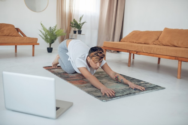 Yoga. Ragazza dai capelli corti che fa yoga a casa e che sembra coinvolta