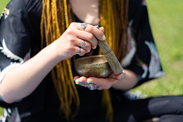 Yogi donna con i dreadlocks che gioca sulla ciotola tibetana o canta la campana dello yoga