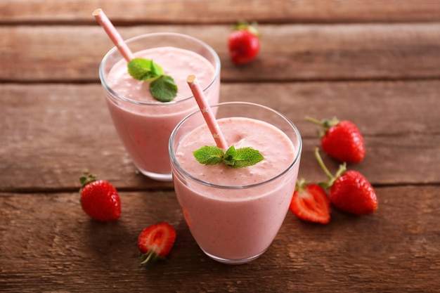 Yogurt alla fragola fresco con frutti di bosco intorno su fondo di legno