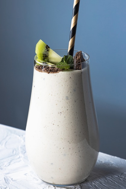 Yogurt alla frutta fatto in casa in tazza di vetro con tubulo all'interno, bevanda dolce al latte con kiwi, banana e cioccolato