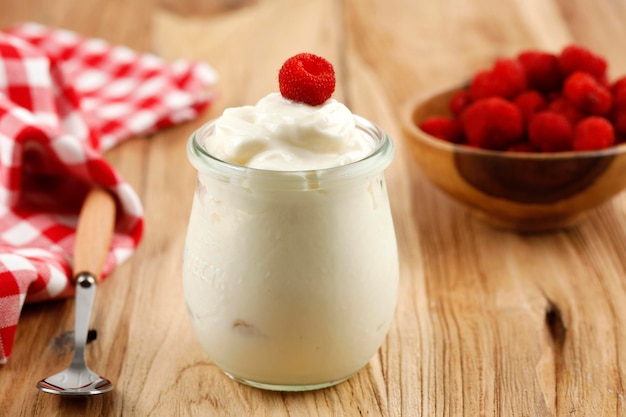 Yogurt bianco con lampone fresco su un barattolo sopra il tavolo di legno Concetto di dieta sana