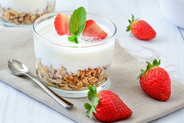 Yogurt con cereali e fragole sul tavolo di legno bianco