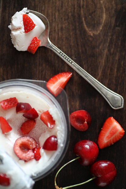 Yogurt con fragole e ciliegie fresche e succose su un tavolo di legno