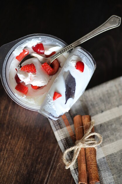 Yogurt con fragole e ciliegie fresche e succose su un tavolo di legno