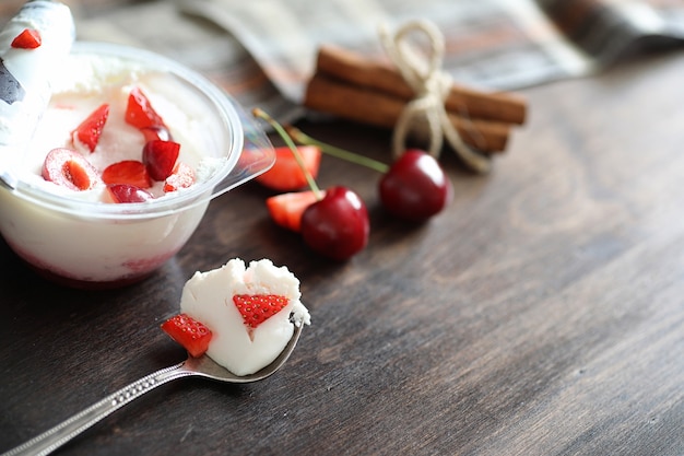 Yogurt con fragole fresche e succose e ciliegie su un tavolo di legno