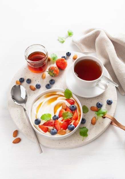 Yogurt con fragole, mirtilli, miele e mandorle per la colazione