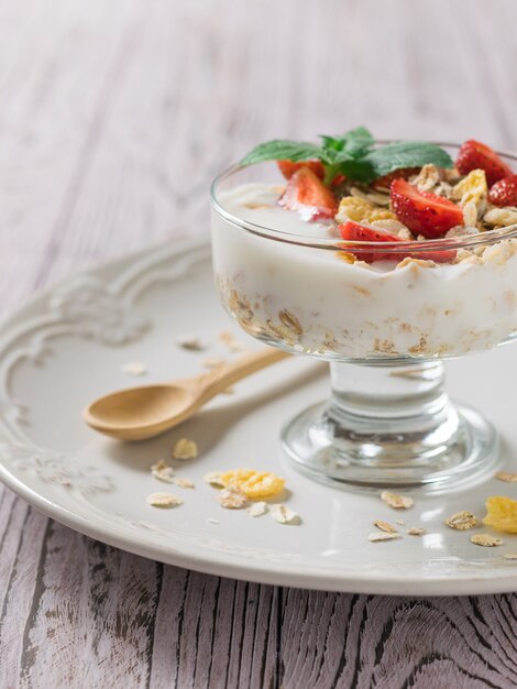 Yogurt con frutti di bosco e menta su un tavolo di legno con un cucchiaio