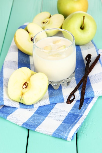 Yogurt delizioso in vetro con la mela sul primo piano di legno della tavola