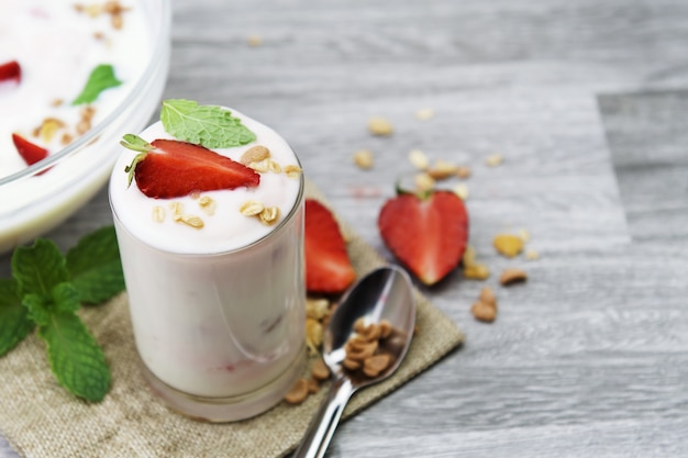 Yogurt e fragola in vetro con la menta sul fondo della tavola