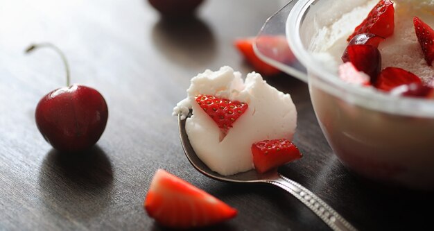 Yogurt fresco con frutti di bosco. Gelato in una ciotola con fragole e ciliegie fresche e succose. Dolce ai frutti rossi.