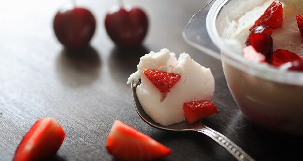 Yogurt fresco con frutti di bosco. Gelato in una ciotola con fragole e ciliegie fresche e succose. Dolce ai frutti rossi.