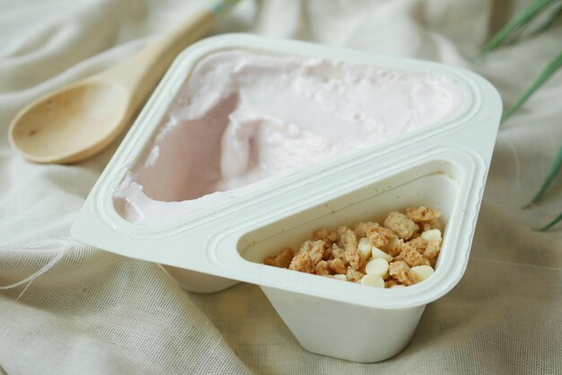 Yogurt fresco in un contenitore di plastica e cucchiaio sul tavolo