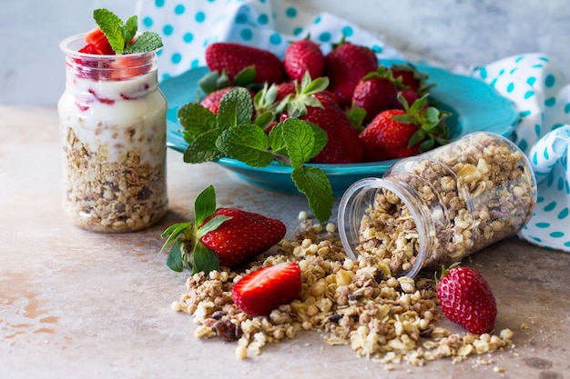 Yogurt greco per la colazione sana fatta in casa con pezzi di muesli fragole fresche sul tavolo di pietra