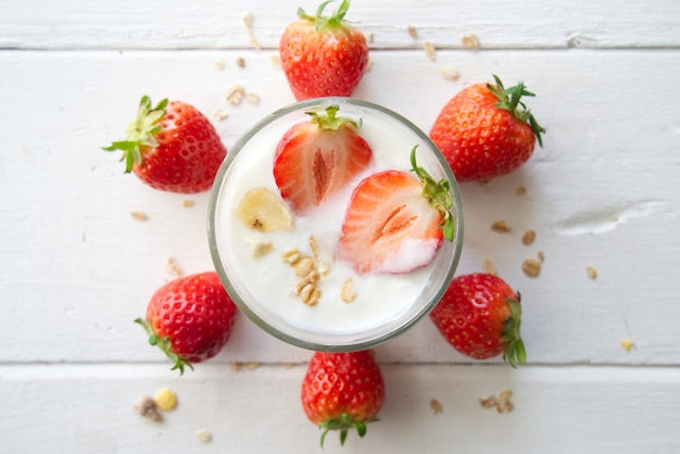 Yogurt greco sano con le fragole e i muesli nel vetro su un vecchio di legno con la tavola.