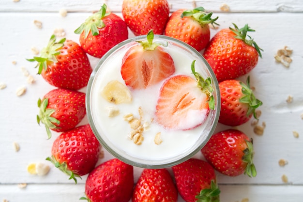 Yogurt greco sano con le fragole e i muesli nel vetro su un vecchio di legno con la tavola.