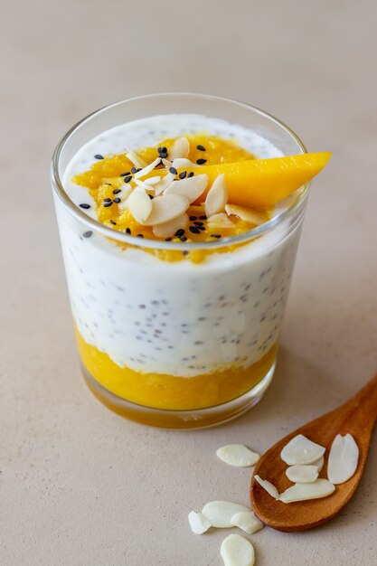 Yogurt in un bicchiere con mango, chia e mandorle. Mangiare sano. Cibo vegetariano. Ricetta. Colazione. Dieta.