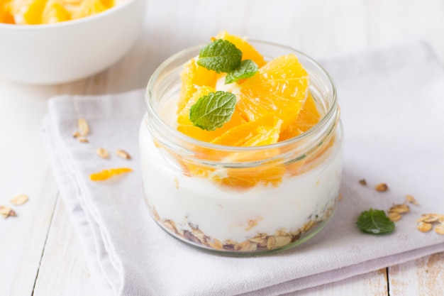 Yogurt, muesli e arancia in barattolo di vetro