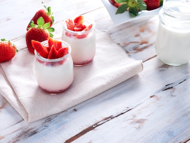 Yogurt naturale con fragole fresche e bicchiere di latte