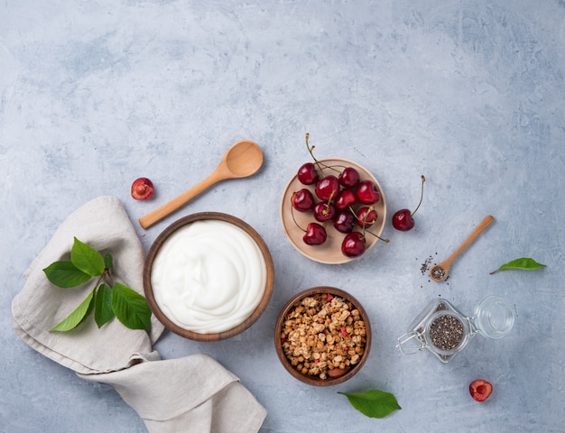 Yogurt naturale con muesli e ciliegia sul tavolo luminoso