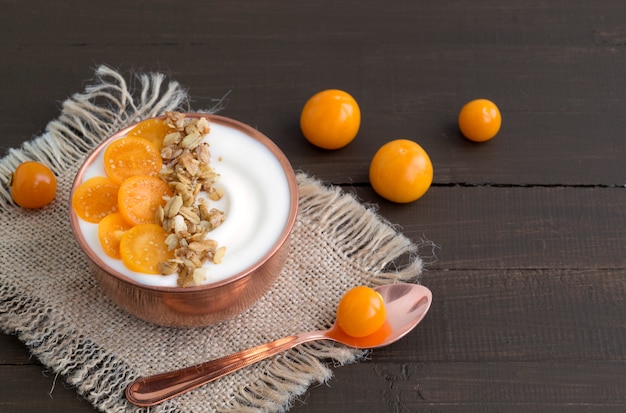 Yogurt naturale fatto in casa con macinata di ciliegia su un tavolo di legno.