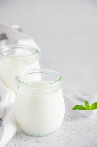 Yogurt organico fresco casalingo in barattoli di vetro su una tavola bianca