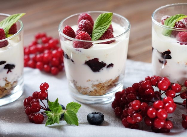 Yogurt sano per la colazione con frutti di bosco freschi e muesli servito in un barattolo di vetro su fondo di legno