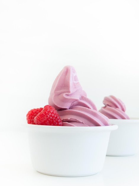 Yogurt soft-serve congelato in tazza su sfondo bianco.