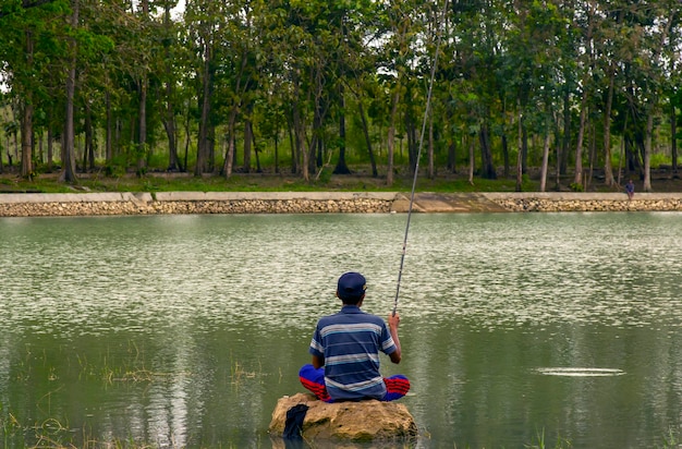 Yogyakarta Indonesia 11 agosto 2022 uomo rilassante e pesca seduto sulla pietra a Gunung Kidul Yogyakarta Indonesia