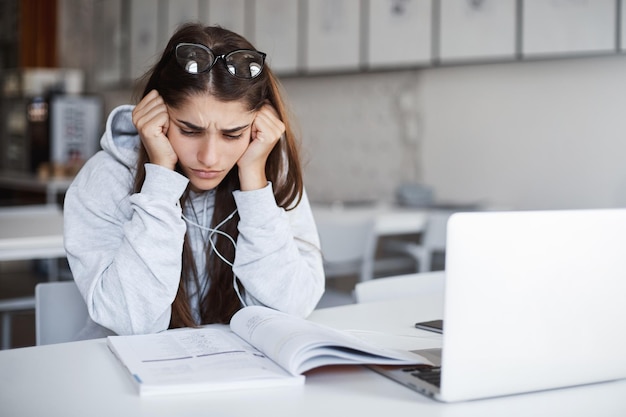 Yound ha perso una studentessa caucasica che guarda nel libro di lavoro non comprendendo l'argomento del prossimo esame