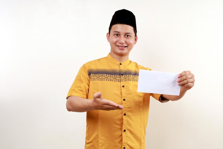Photo young asian muslim man holding envelope filled with money give thr or donation or zakat fitrah as an obligation in the holy month of ramadan
