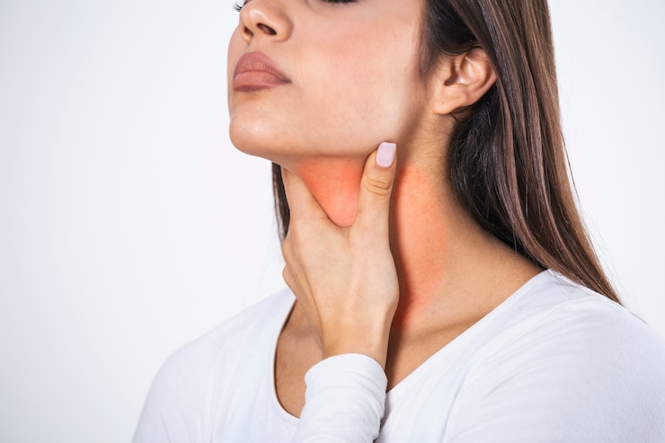 Young beautiful woman suffering from pain in throat, touching inflamed zone on her neck